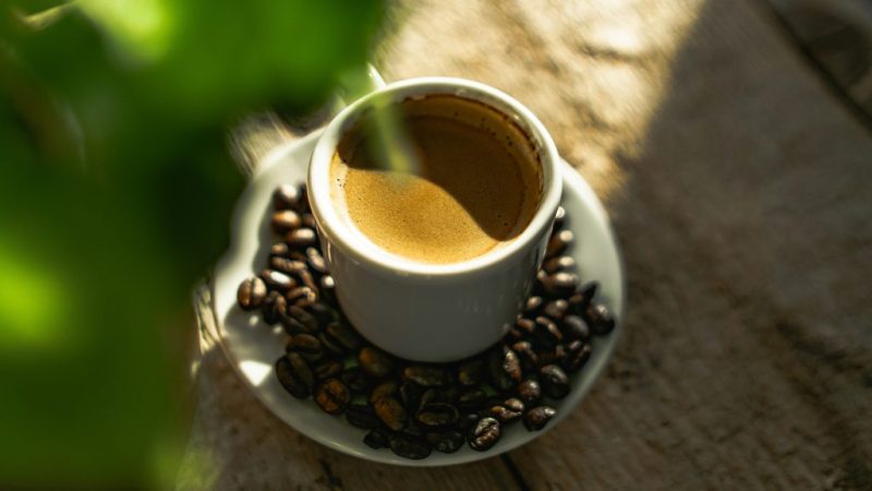 فنجانی قهوه در فضای آزاد با دانه های زیبای آن