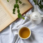 فنجان و قوری چای سبز در کنار کتاب