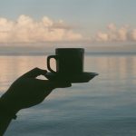 نمایی از یک فنجان نوشیدنی گرم با پشت صحنه آبی دریا