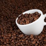 فنجان سفید روی دانه های قهوه