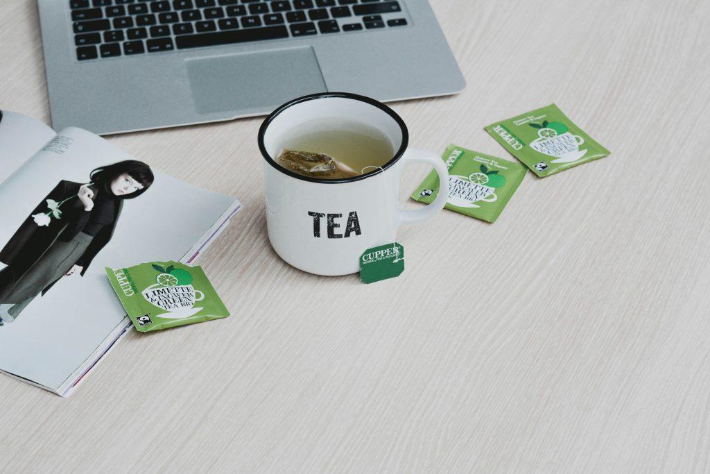 لیوان چای کنار لپتاپ روی میز برای تحقیق