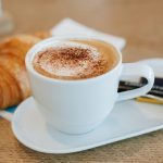 کاپوچینو و کروسانت روی میز صبحانه