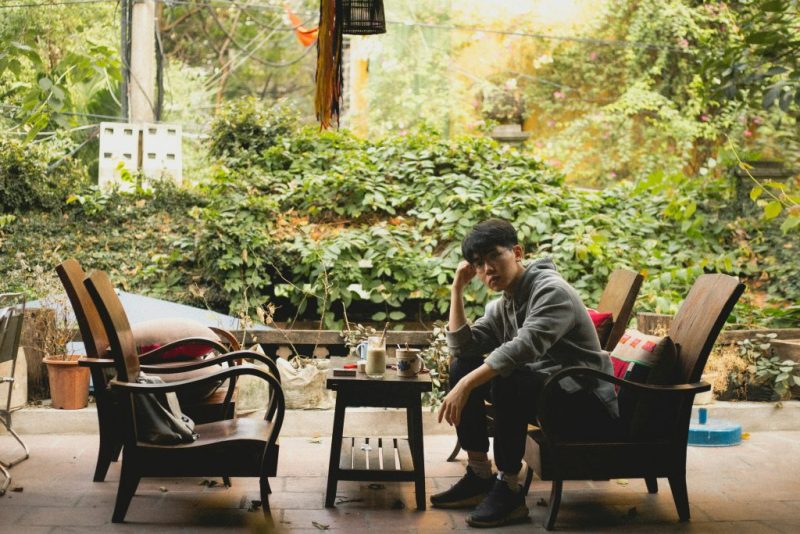 یه مرد آسیای شرقی روی صندلی های یک کافه در فضای باز