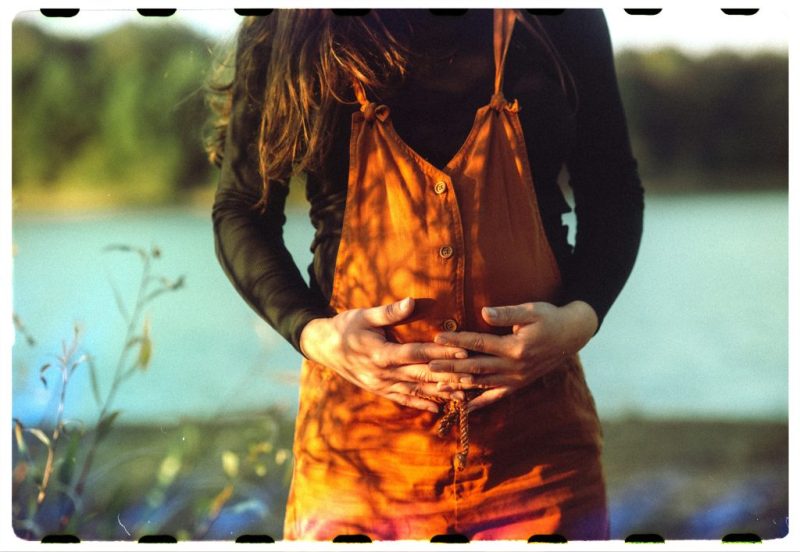 دختری با لباس اورآل نارنجی که درد پریود دارد