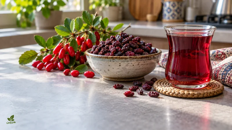 میوه تازه و زرشک خشک تیره کنار یک لیوان نوشیدنی زرشک